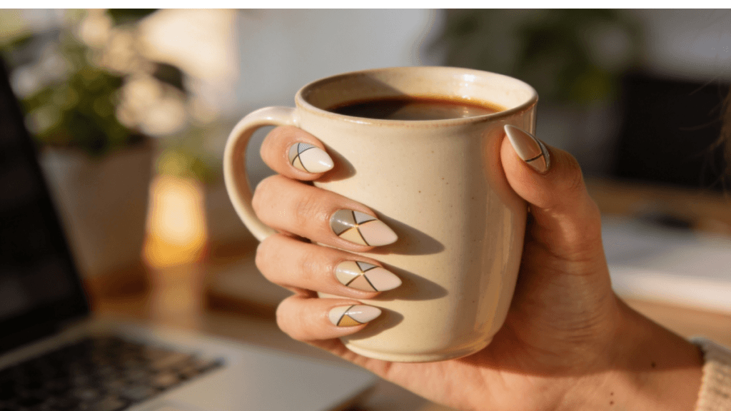 Professional woman showing modern nail art trends 2026 while holding coffee